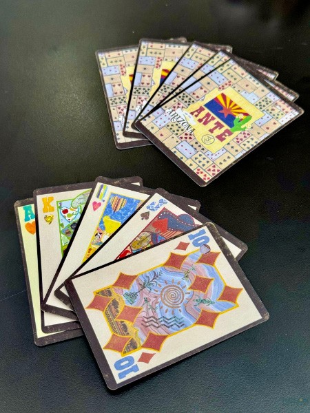 Arizona ANTE playing cards fanned on a black table with collage backs and face cards by Suzanne J. Villella