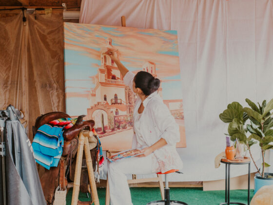 Camila Ibarra paints a majestic castle scene on a large canvas at her studio, focused and absorbed in her art.