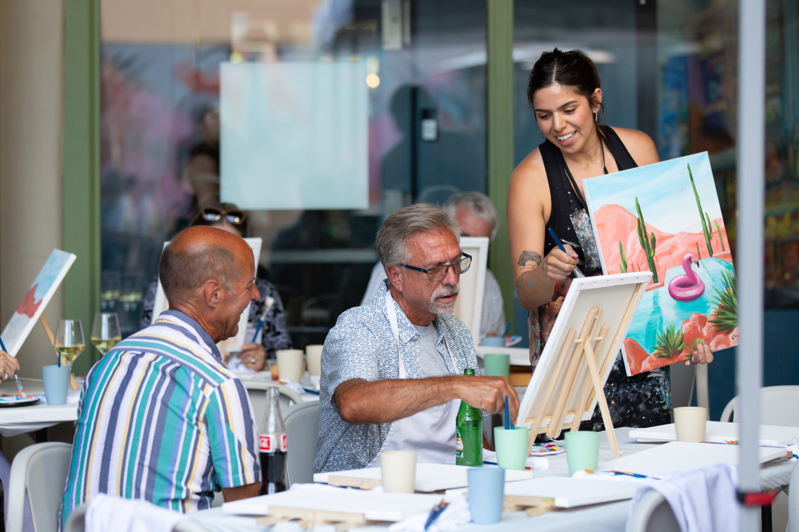 Camila Ibarra teaching an art class during a Gay Pride LGBT Paint and Sip event at Tucson Gallery, showcasing LGBTQ art in downtown AZ.