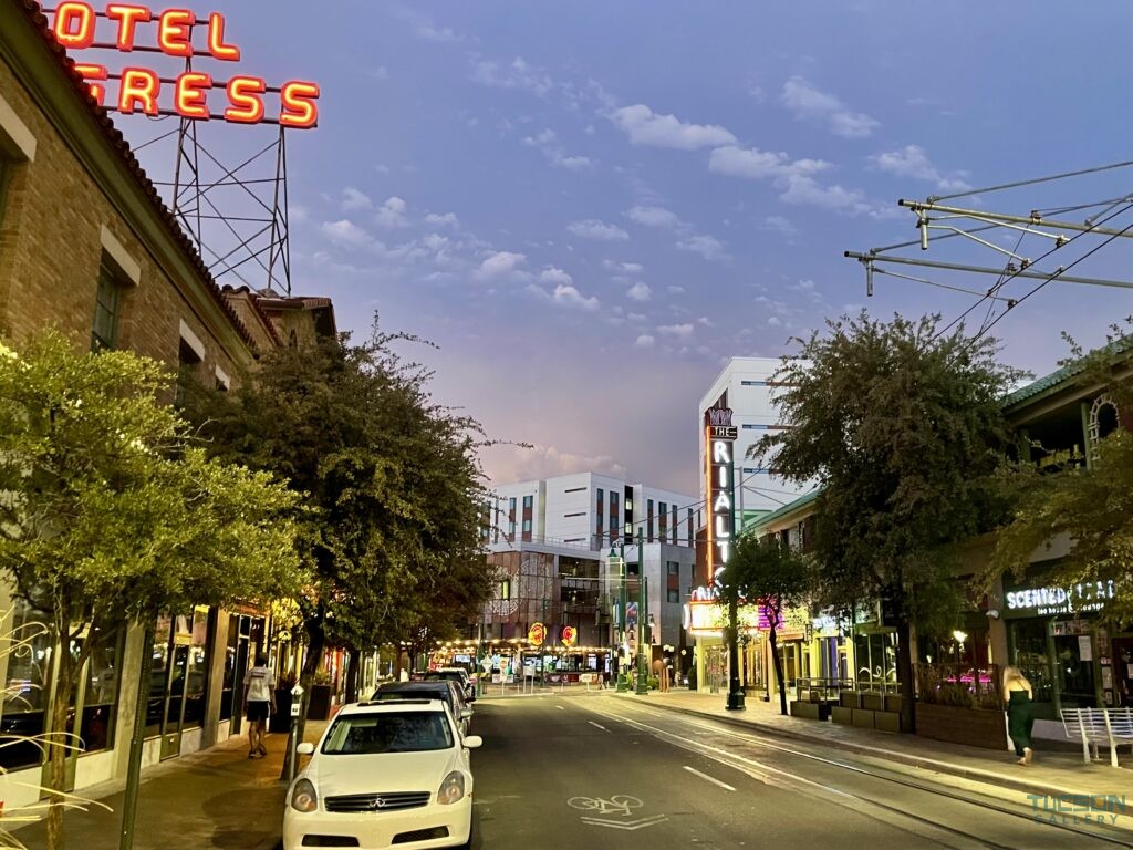 Night photo of people and cars in Downtown Tucson, highlighting the vibrant art gallery scene featuring local artists and muralists.