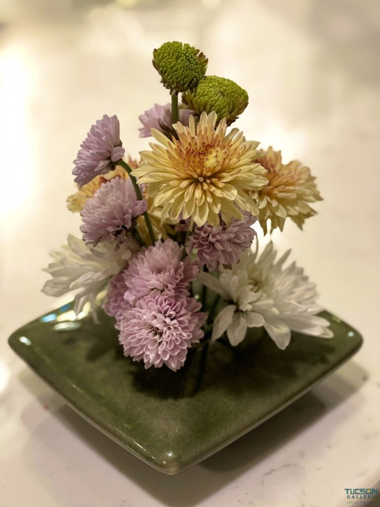 Delicate Japanese ikebana floral design in olive green vase