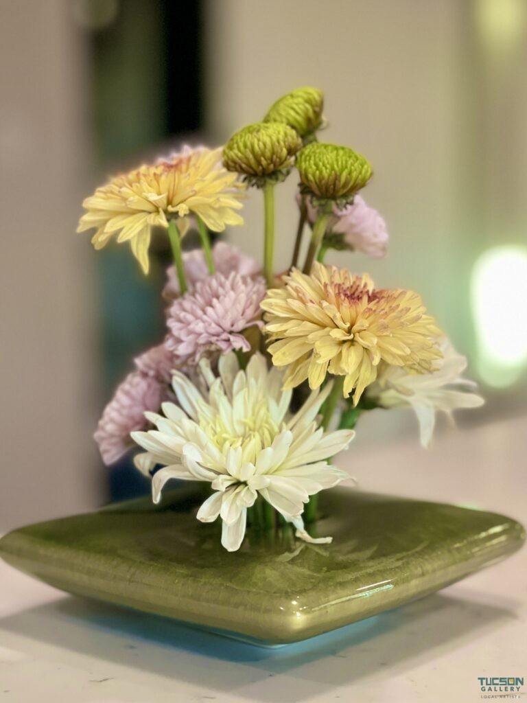 Elegant ikebana floral arrangement in a green ceramic vase