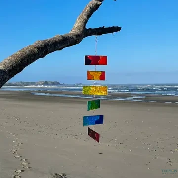 Rainbow Resin Mobile hanging from a tree branch above a beach, showing colorful resin panels in sunlight