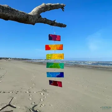 Colorful Rainbow Resin Mobile hanging outdoors over a sandy beach with ocean in the background